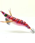 Señuelo jibionera para pesca de cefalópodos, diseño realista con cuerpo segmentado, ojos prominentes y corona de anzuelos múltiples. Ideal para atraer sepias y calamares en aguas costeras. Modelo con patrón rosa y rayas lilas, blancas y plata, plumas laterales y aleta metálica para mayor estabilidad.
