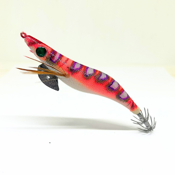 Señuelo jibionera para pesca de cefalópodos, diseño realista con cuerpo segmentado, ojos prominentes y corona de anzuelos múltiples. Ideal para atraer sepias y calamares en aguas costeras. Modelo color rosa con patrón negro y lila fluor, plumas laterales y aleta metálica para mayor estabilidad.